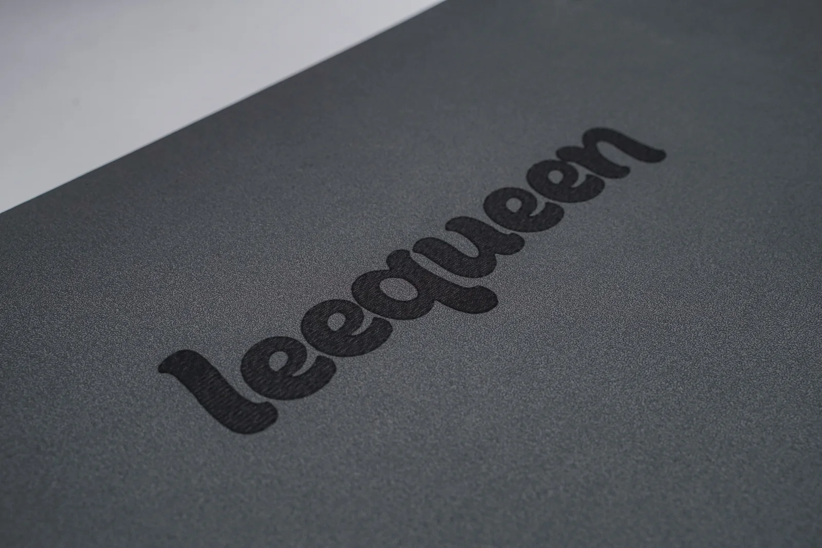 Cận cảnh bề mặt thảm màu xám và logo Leequeen