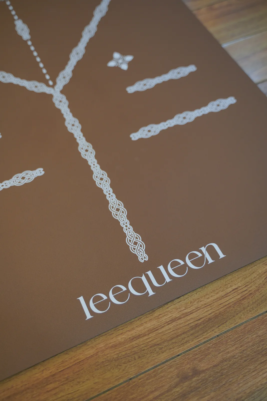 Cận cảnh mặt thảm Leequeen màu nâu với logo và đường định tuyến màu sáng